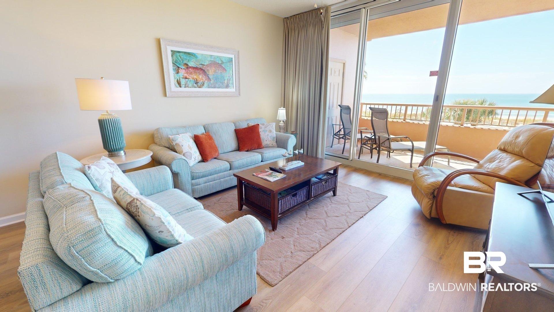 Image 2: Living area with light wood finished floors, a water view, and floor to ceiling windows