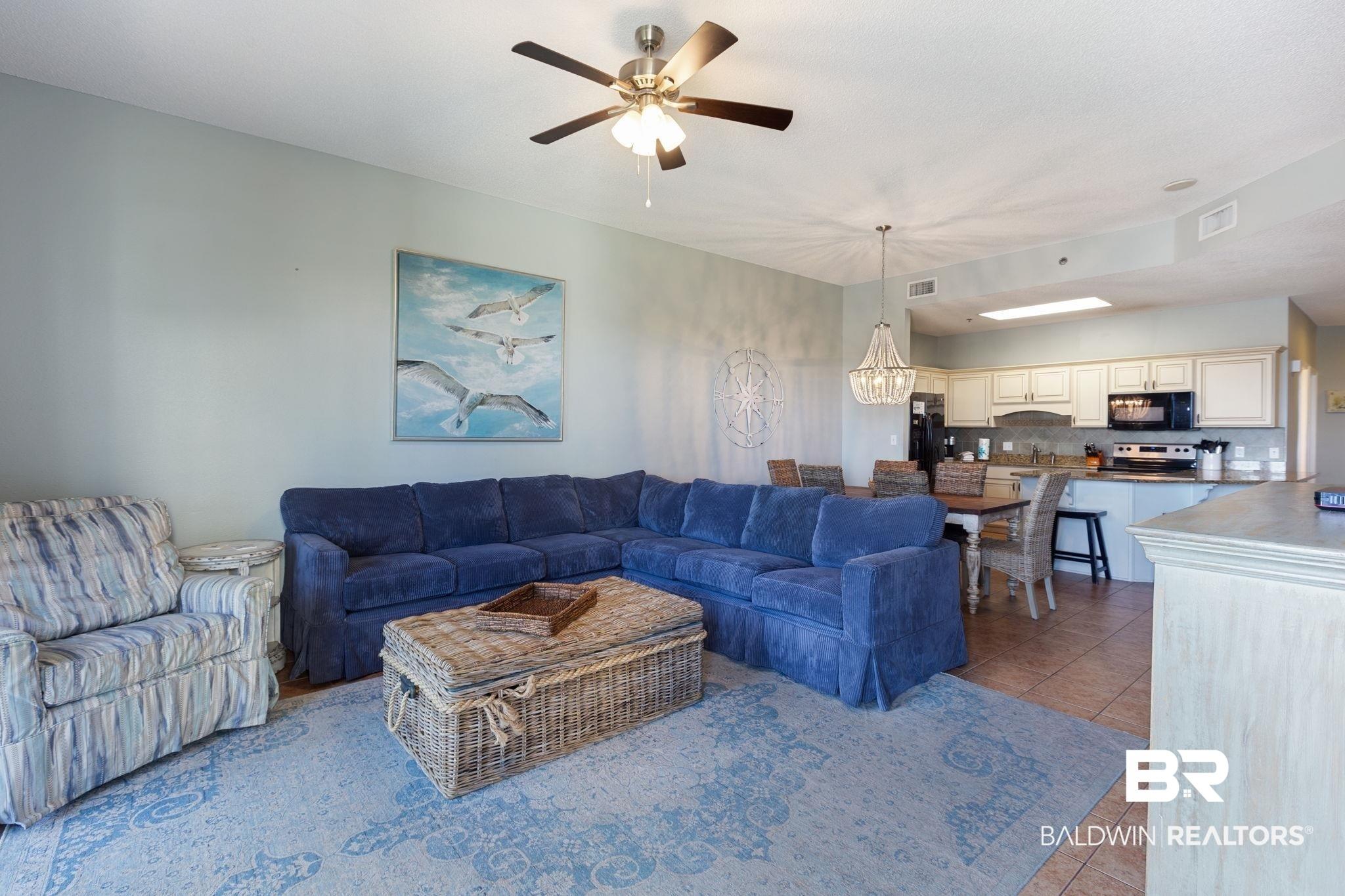 Image 2: Living area featuring light tile patterned flooring, a chandelier, and ceiling fan