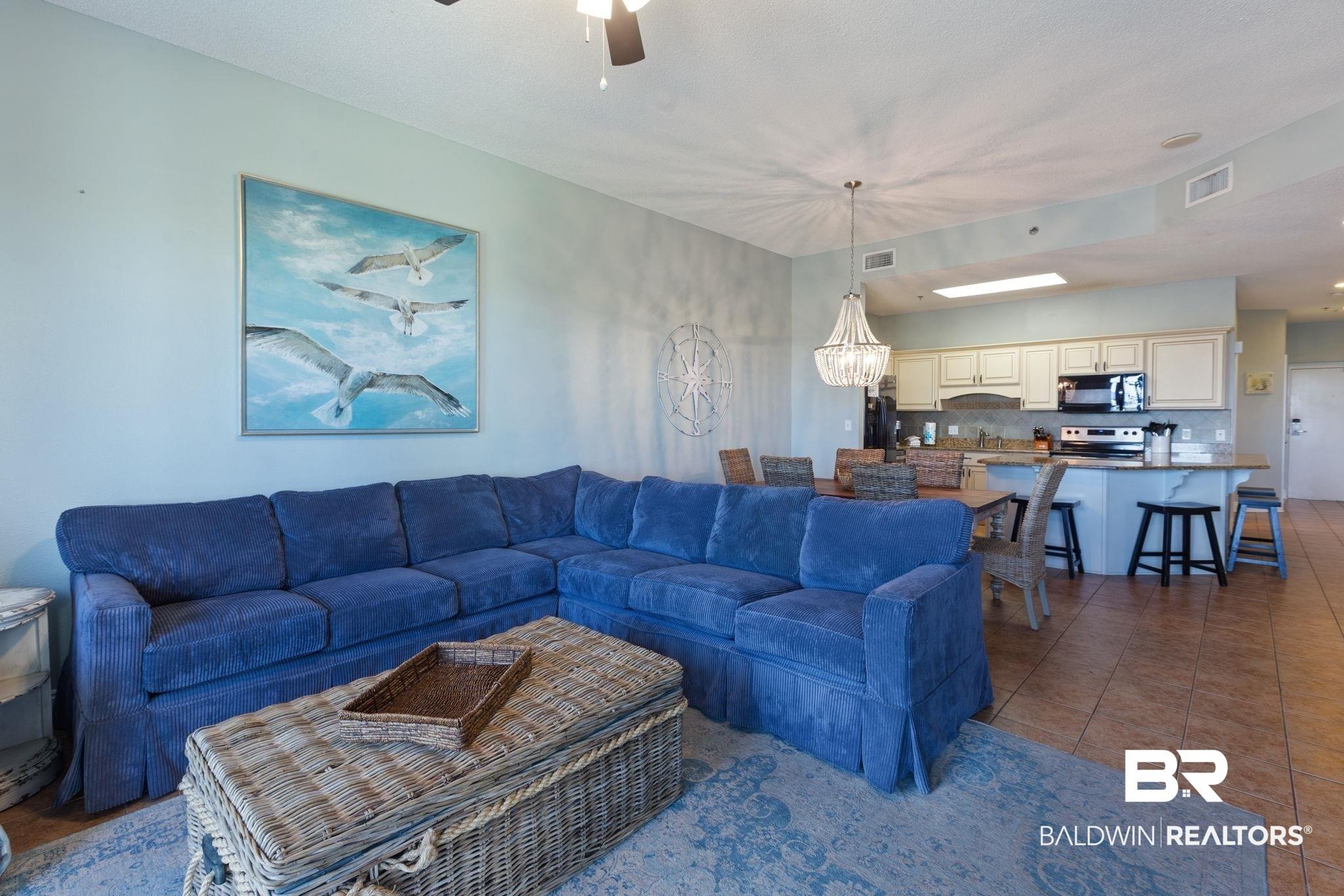 Image 3: Living room featuring a chandelier, dark tile patterned flooring, and ceiling fan