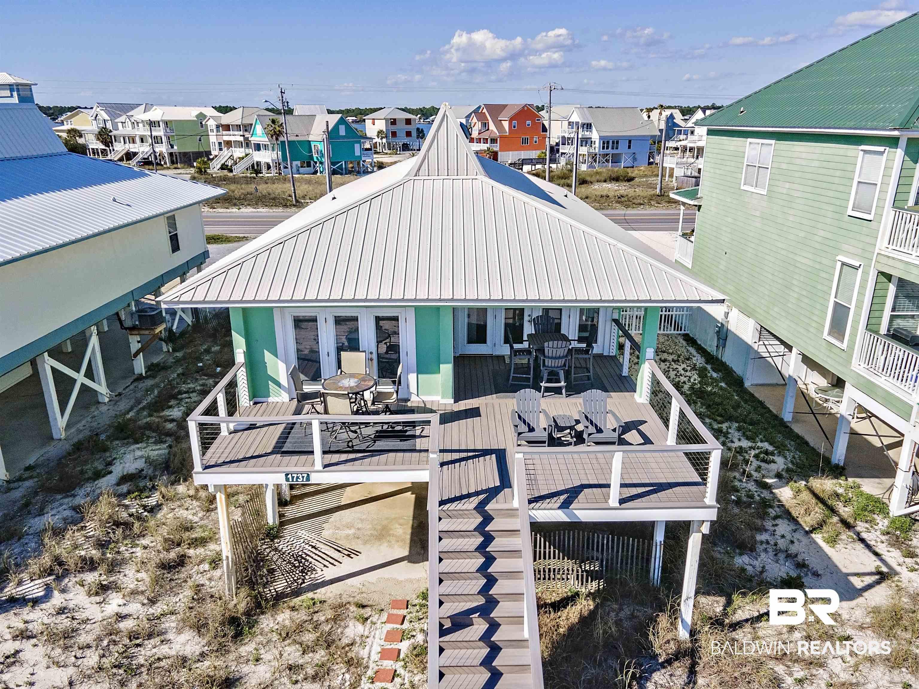 Image 1: Back of property with a deck, a metal roof, outdoor dining space, and a residential view
