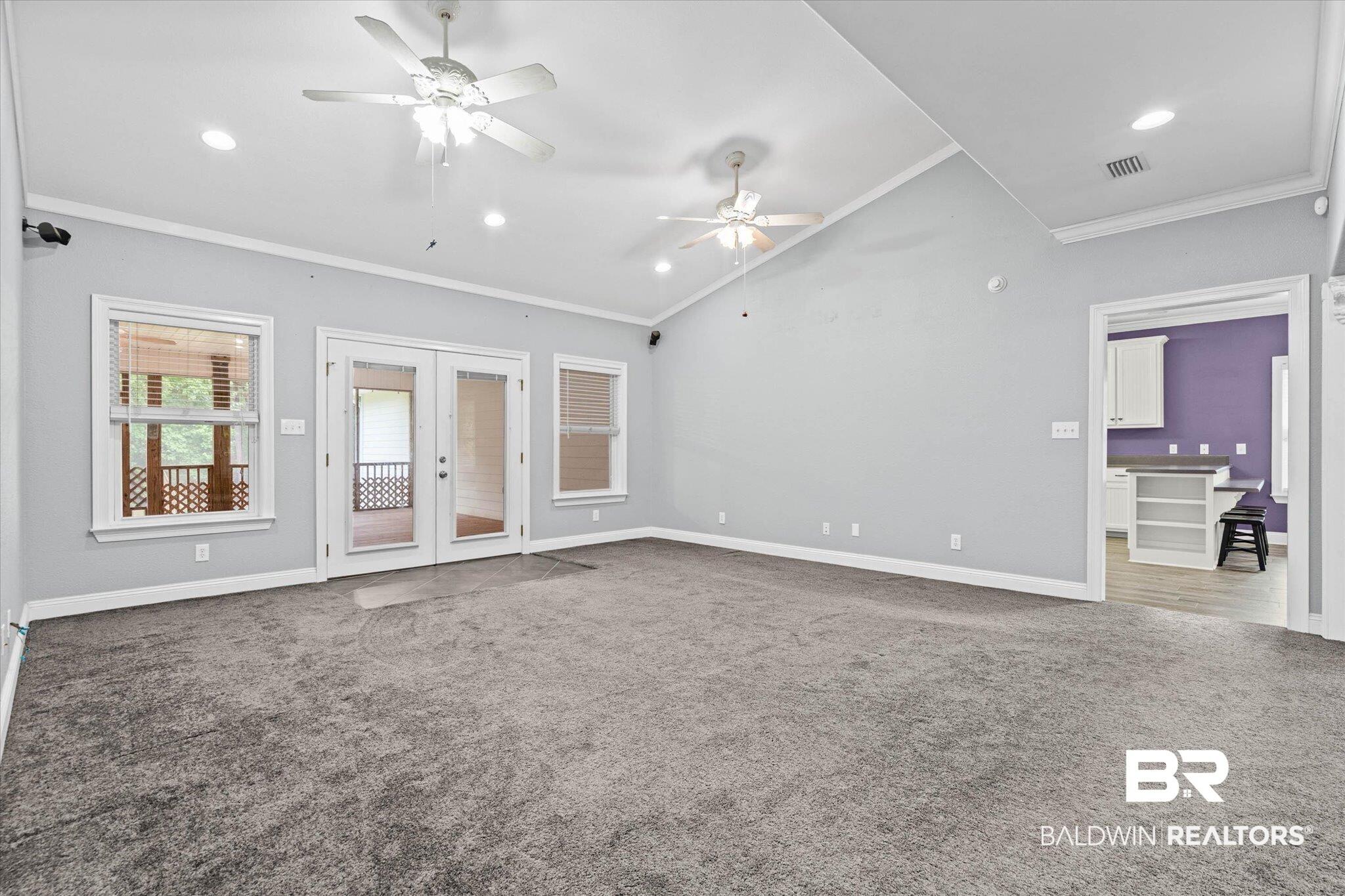 Image 3: Spacious interior featuring a vaulted ceiling with recessed lighting, multiple ceiling fans, and neutral gray carpet
