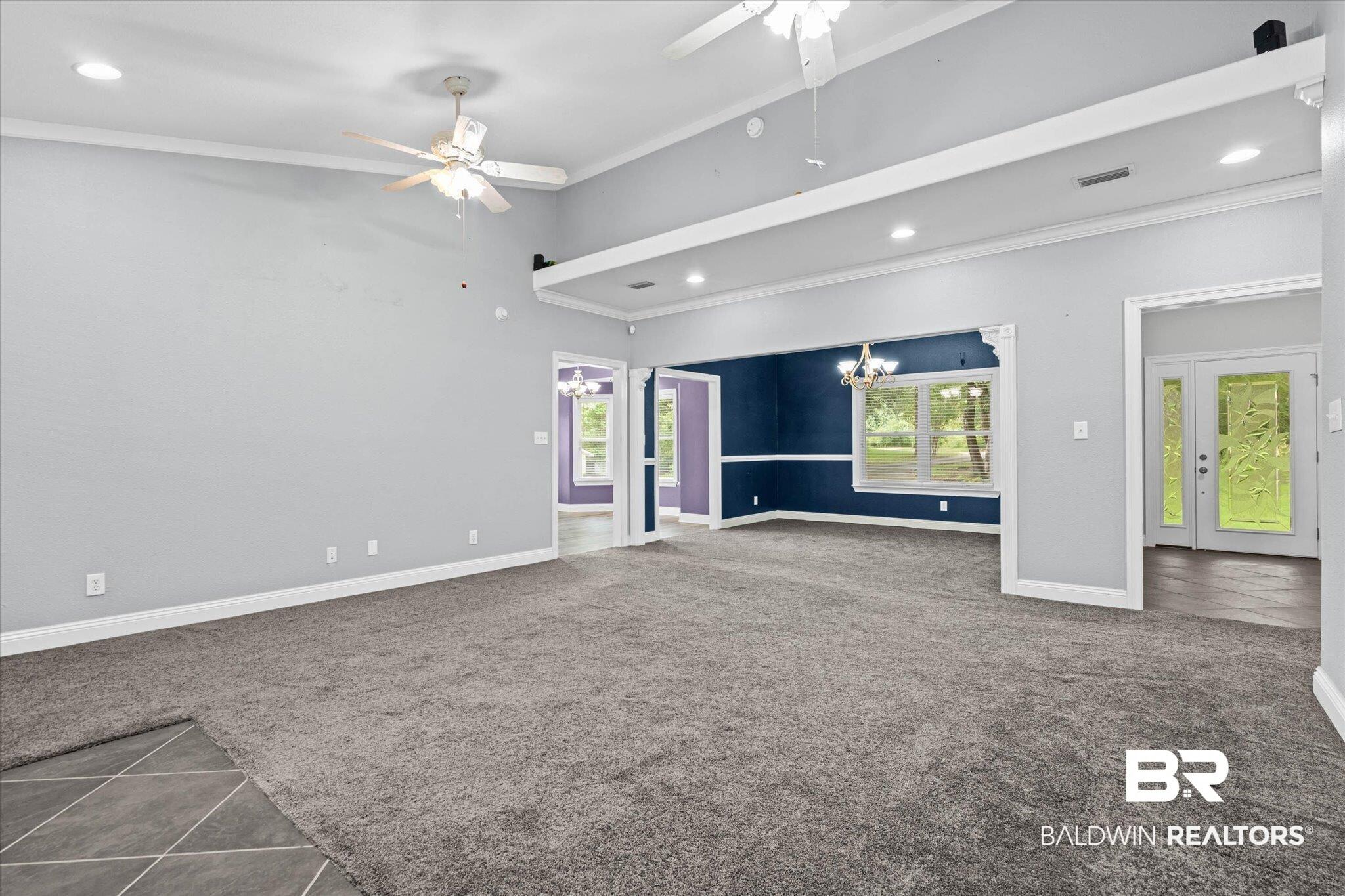 Image 4: Spacious living area featuring carpet flooring, vaulted ceilings, and dual ceiling fans