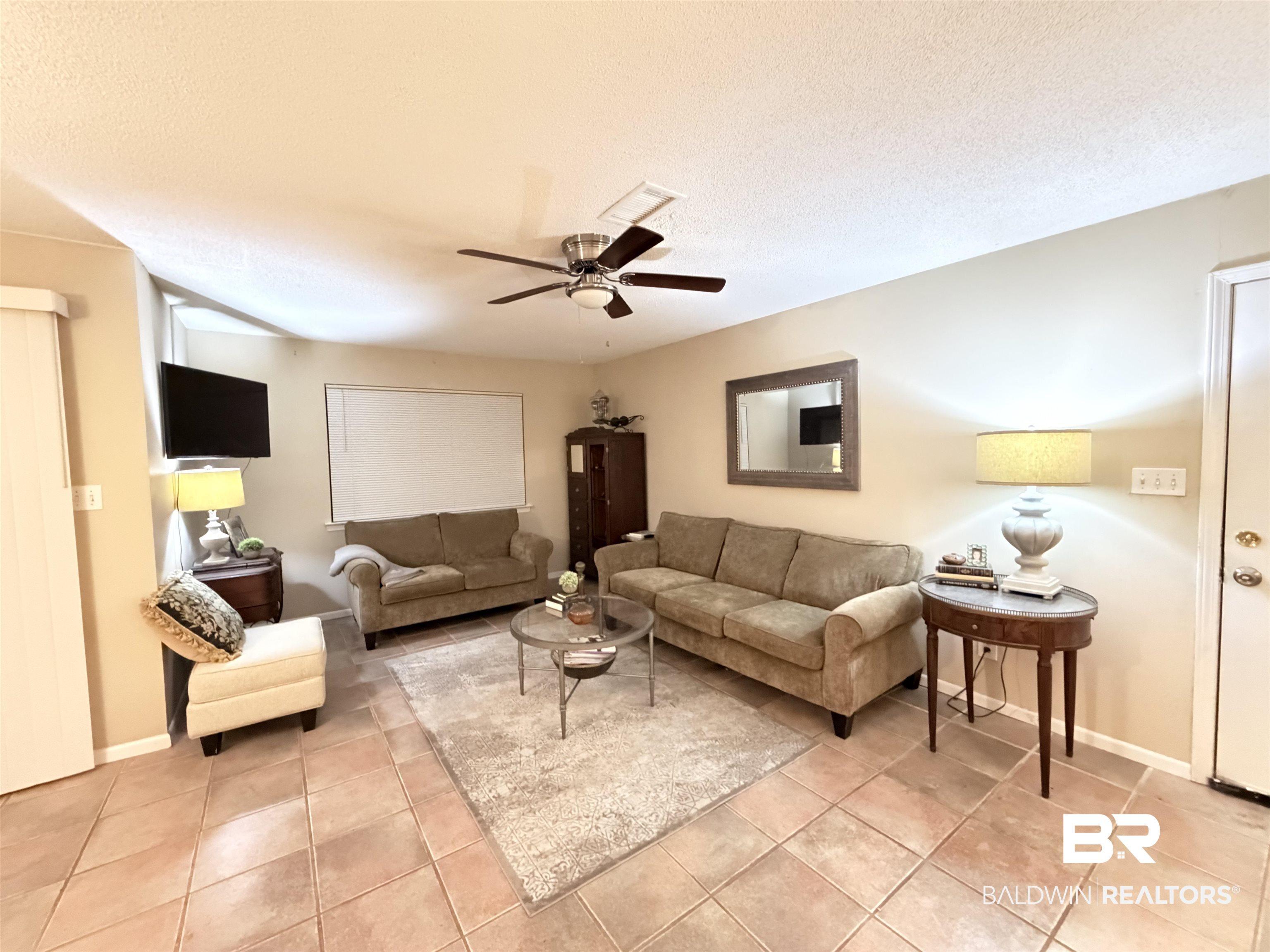 Image 2: Living area with ceiling fan, a textured ceiling, and light tile patterned floors
