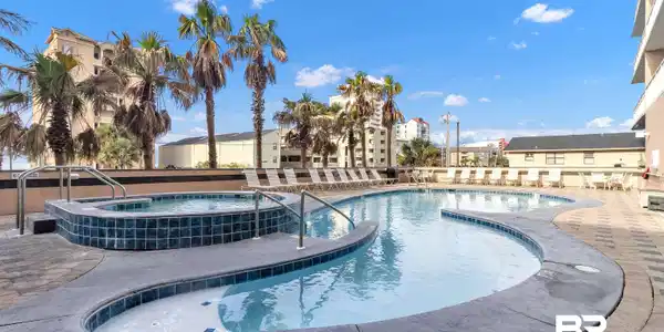 Image 3: Resort-style outdoor pool area featuring a freeform swimming pool, integrated spa, and expansive paver deck