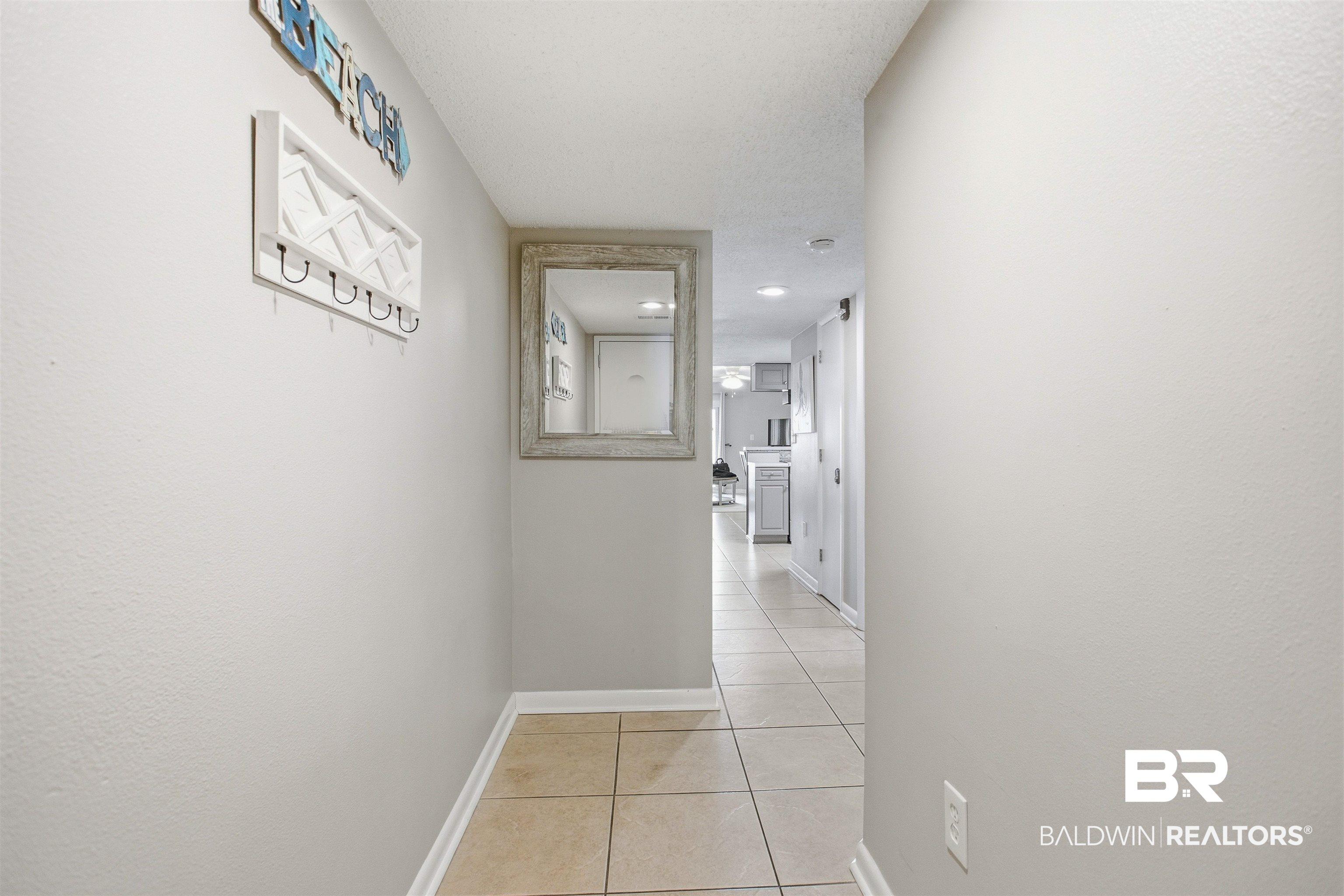 Image 2: Hallway featuring light neutral wall paint, tile flooring, and white trim