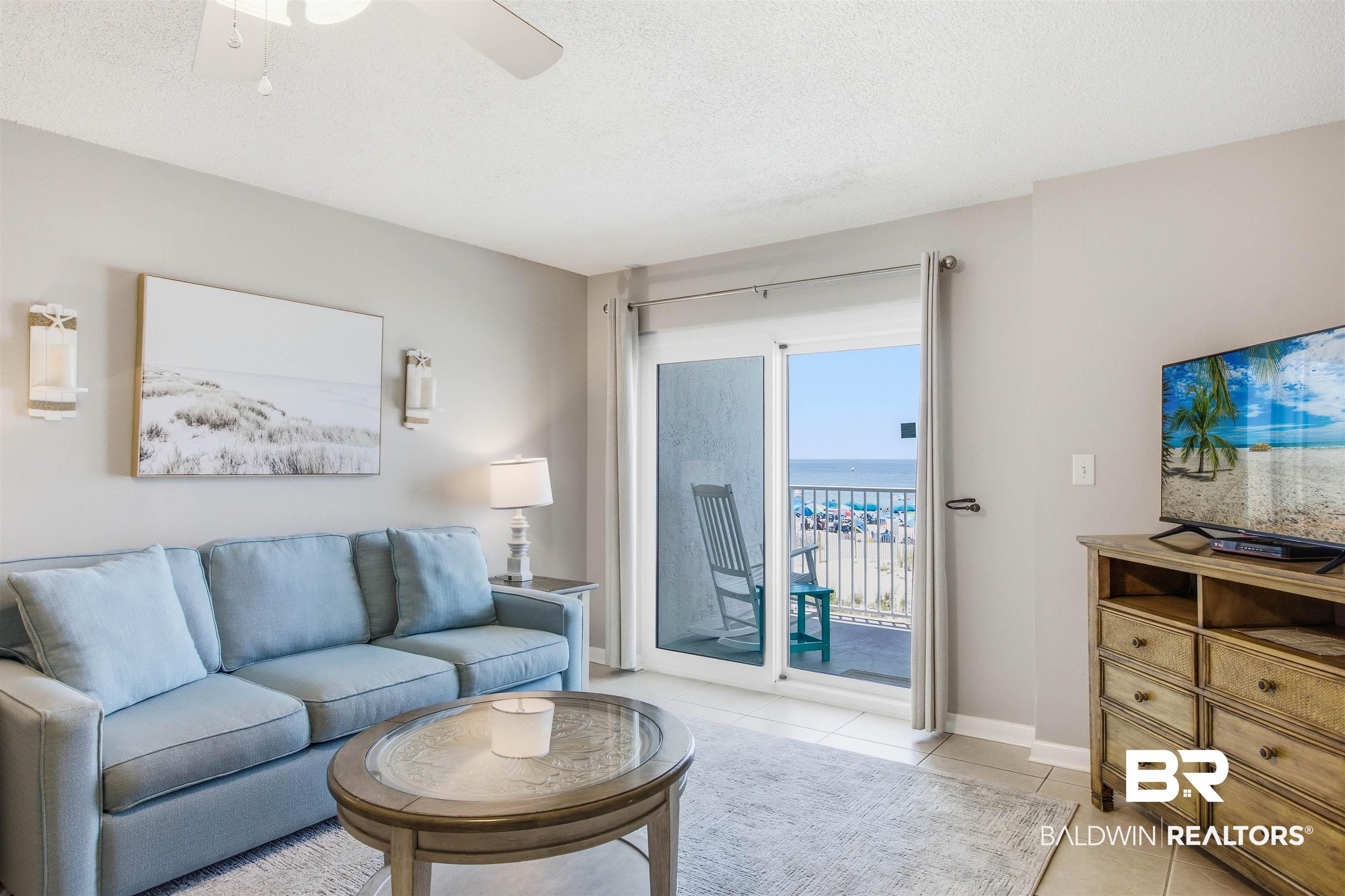 Image 4: Sliding glass doors open to an outdoor balcony with metal railings and expansive ocean scenery