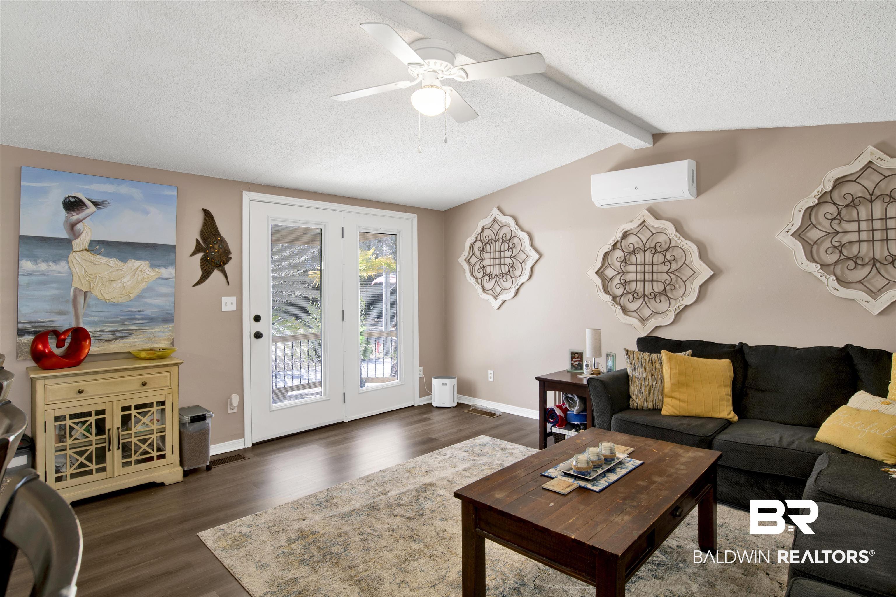 Image 4: Living area with a textured ceiling, dark wood-style flooring, ceiling fan, and a wall unit AC