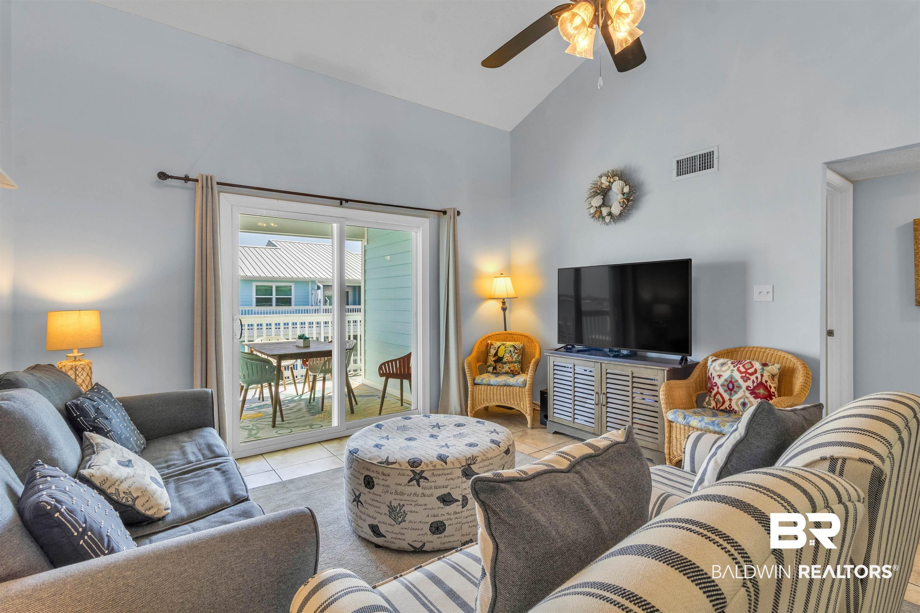 Image 4: Living area with lofted ceiling, light tile patterned flooring, and a ceiling fan