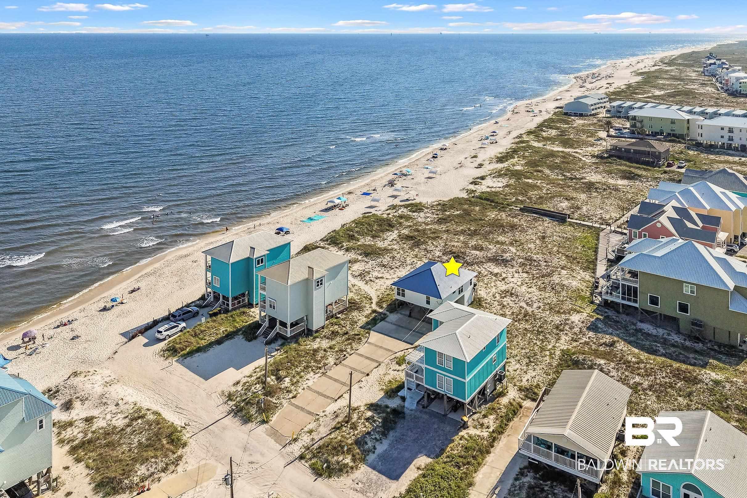 Image 1: Coastal property featuring direct beach access, an elevated structure, a metal roof, and surrounding natural landscaping