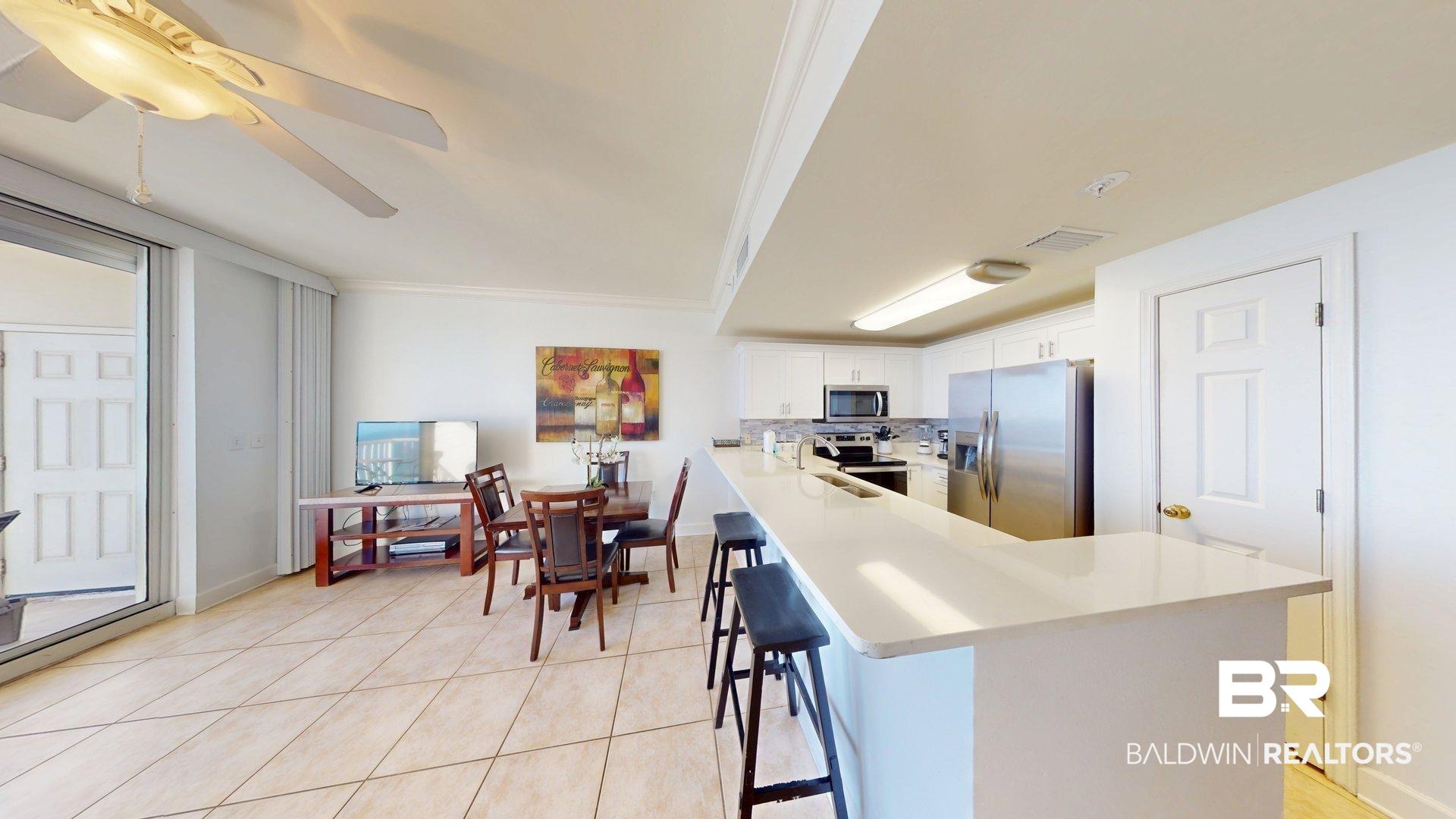 Image 4: Kitchen featuring a kitchen breakfast bar, stainless steel appliances, ceiling fan, white cabinetry, and light tile patterned flooring