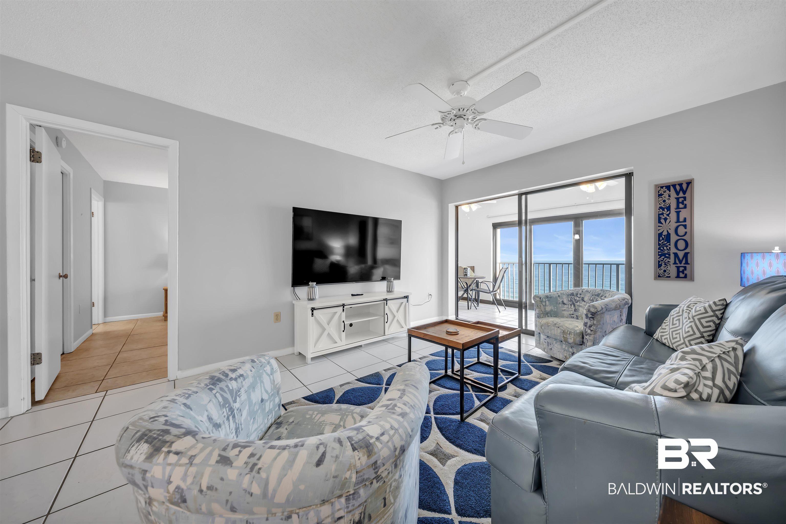 Image 3: Living area with a ceiling fan and light tile patterned floors
