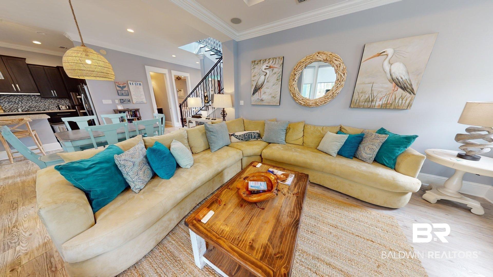 Image 3: Open-concept living area featuring light wood-finish flooring, a contemporary staircase, and a kitchen with dark cabinetry and a tile backsplash