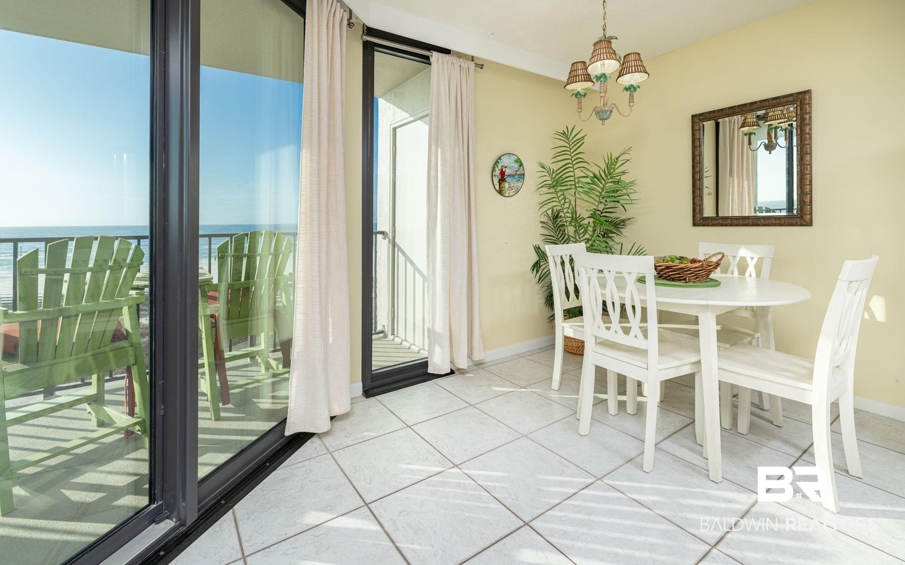 Image 2: Dining space with suspended lighting, light tile patterned floors, and a water view