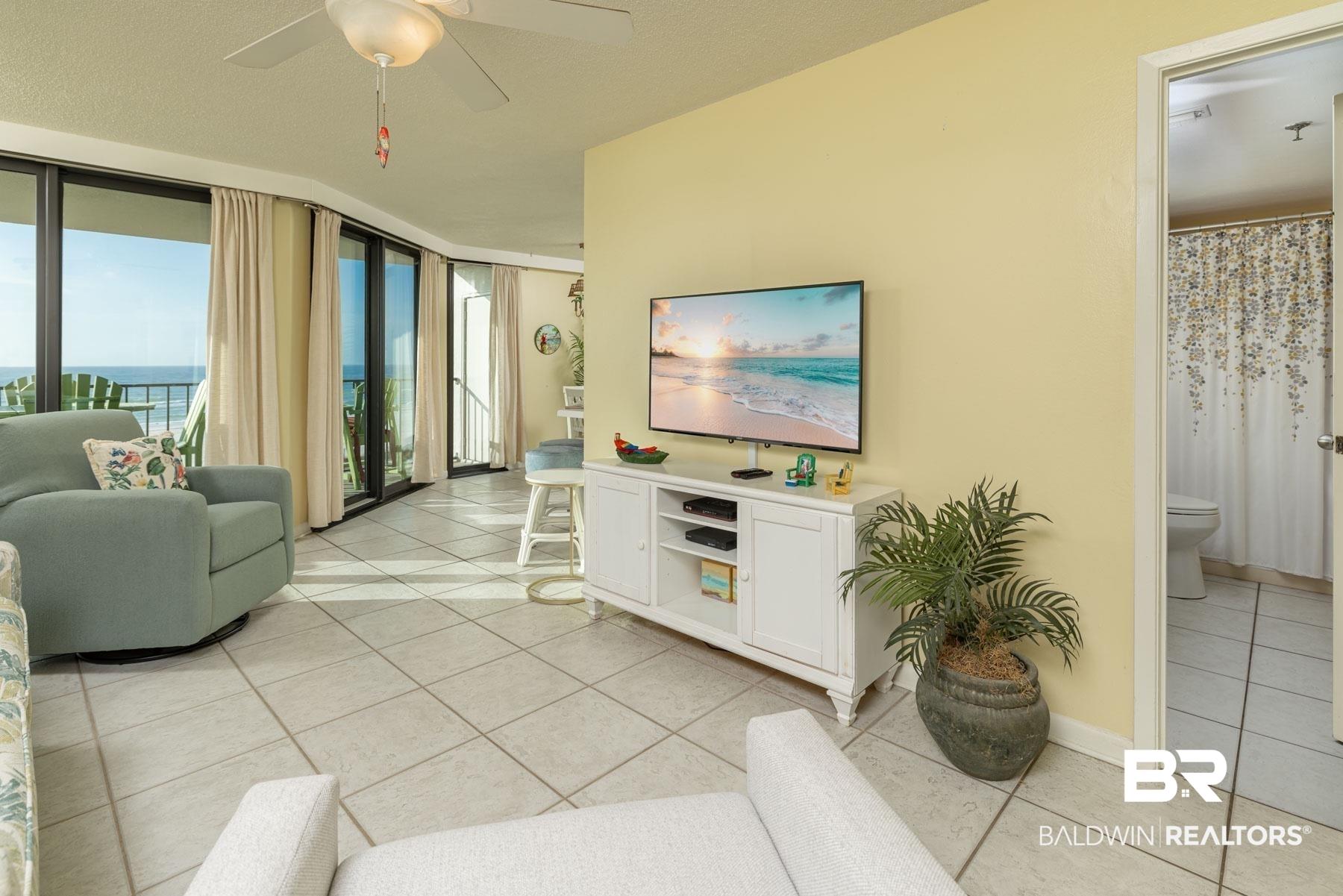 Image 4: Living area with light tile patterned floors, floor to ceiling windows, ceiling fan, and a water view