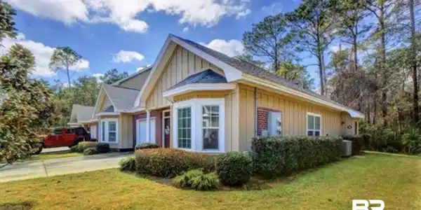 Image 2: Exterior featuring bay windows, vertical board and batten siding, brick accents, and a shingled roof