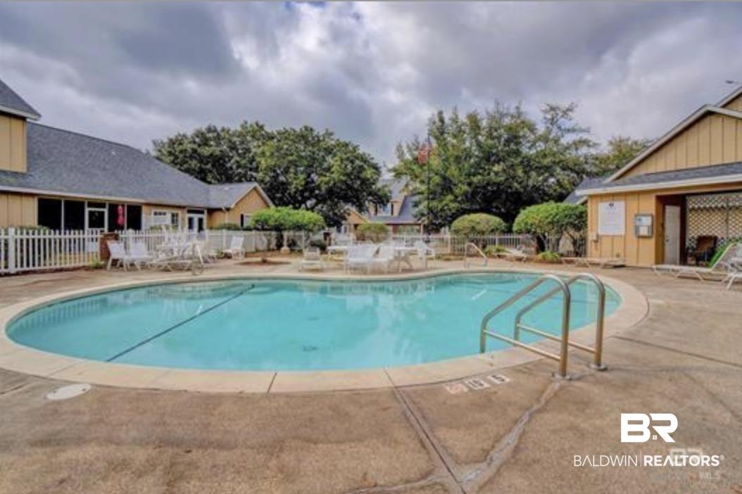 Image 4: Inviting swimming pool with concrete decking, surrounding buildings featuring siding, and mature landscaping