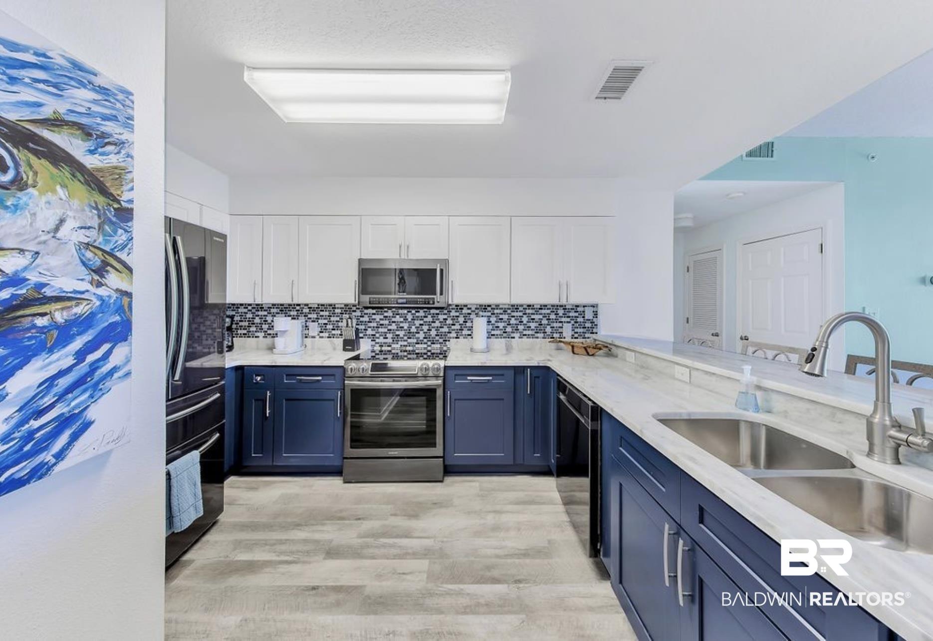 Image 3: Kitchen with tasteful backsplash, white cabinets, sink, appliances with stainless steel finishes, and light hardwood / wood-style flooring