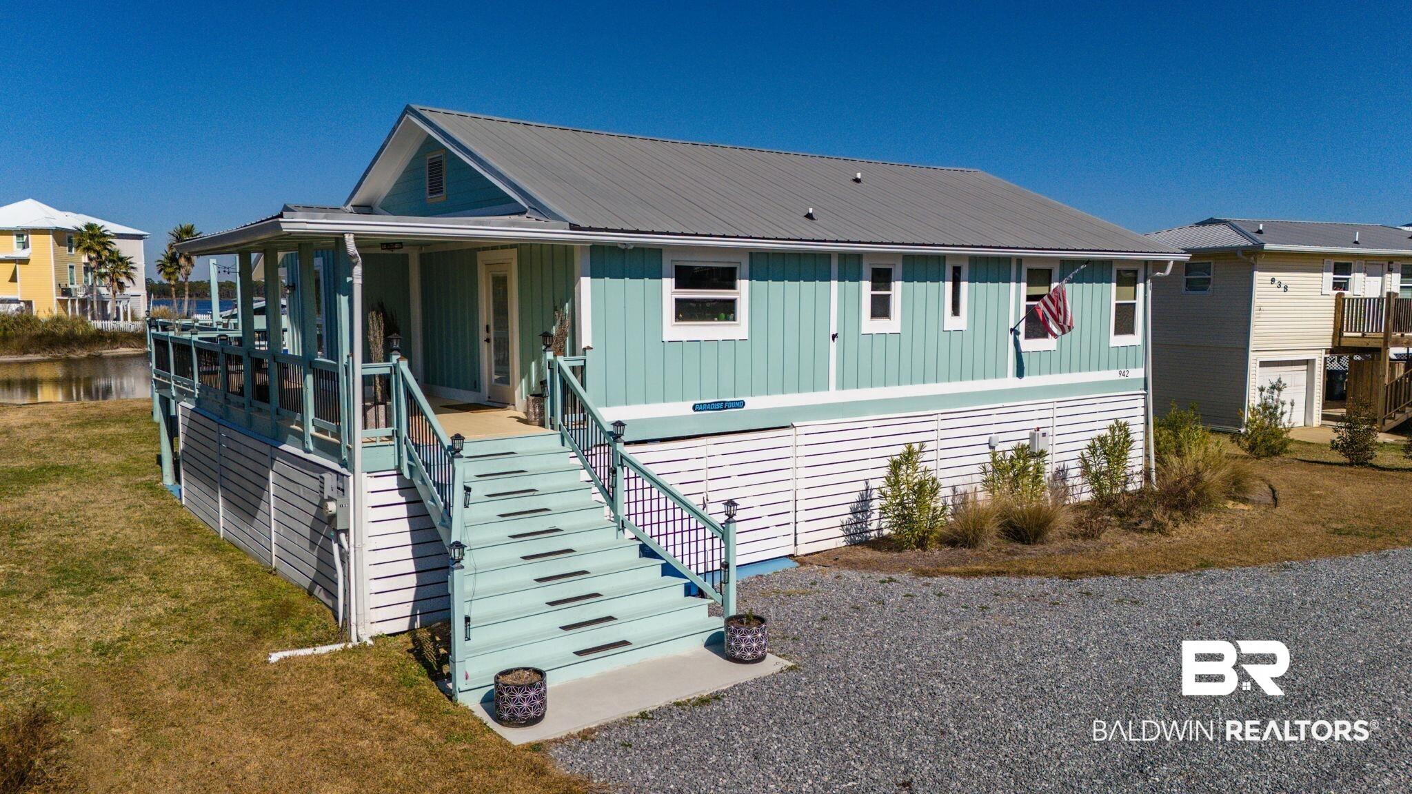 Image 3: View of front of house with board and batten siding, covered porch, a front lawn, and a metal roof