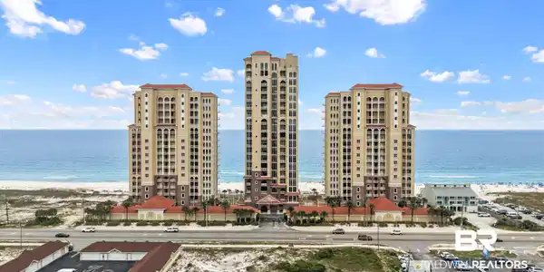 Image 3: Three high-rise buildings featuring a stucco exterior with red tile roofs, situated directly on a sandy beachfront