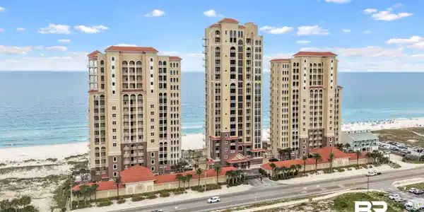 Image 4: Coastal high-rise residences featuring Mediterranean Revival architecture, multiple balconies, a terracotta tile roof, and a direct beachfront location
