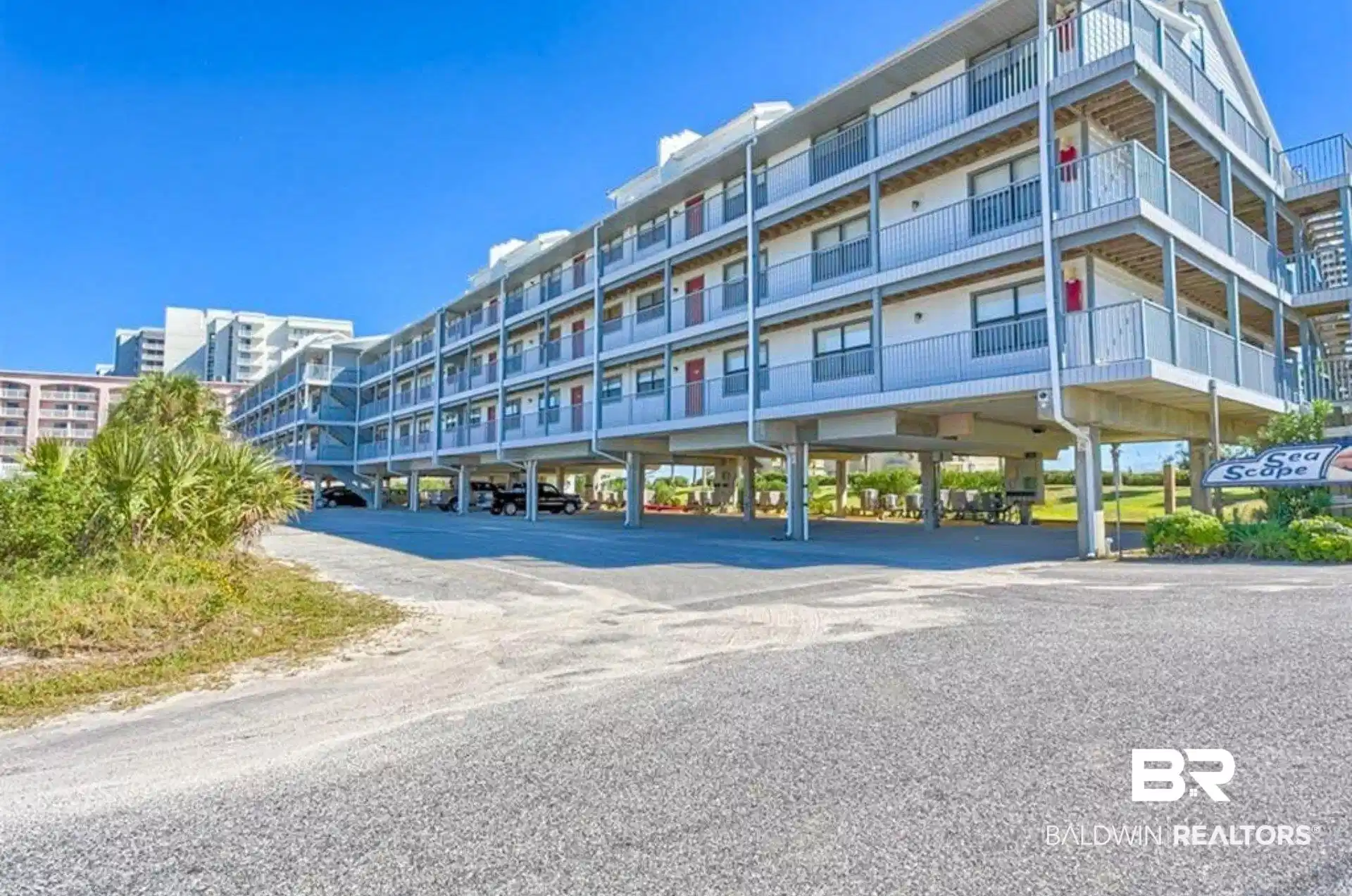 Image 1: Multi-story building featuring white siding and multiple private balconies with metal railings
