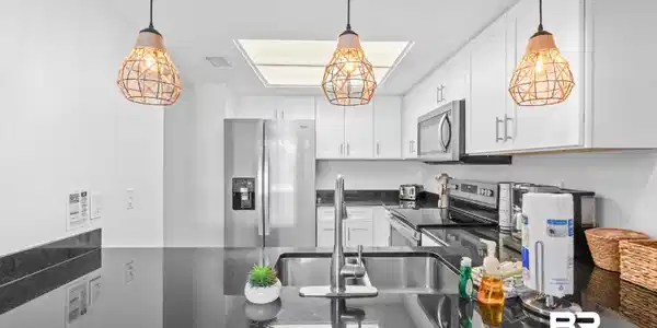 Image 4: Kitchen featuring white shaker-style cabinetry, dark countertops, stainless steel appliances, and a skylight