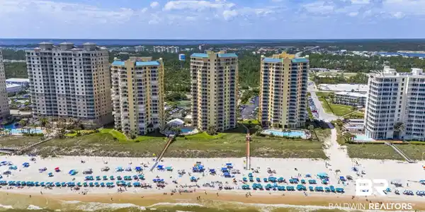 Image 3: Beachfront high-rise condominiums featuring multiple balconies, resort-style swimming pools, and direct access to the sandy beach