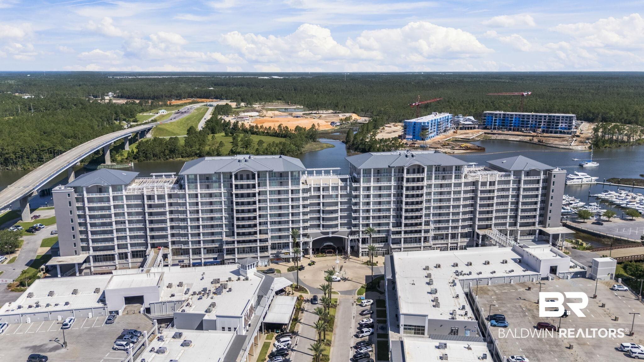 Image 4: Multi-story waterfront condominium building featuring numerous balconies, a prominent entrance archway, and an adjacent marina