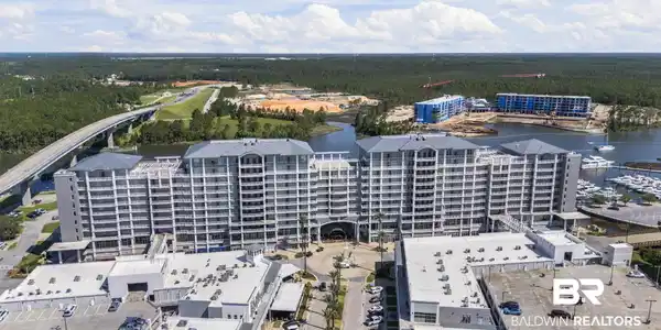 Image 4: Multi-story waterfront condominium building featuring numerous balconies, a prominent entrance archway, and an adjacent marina