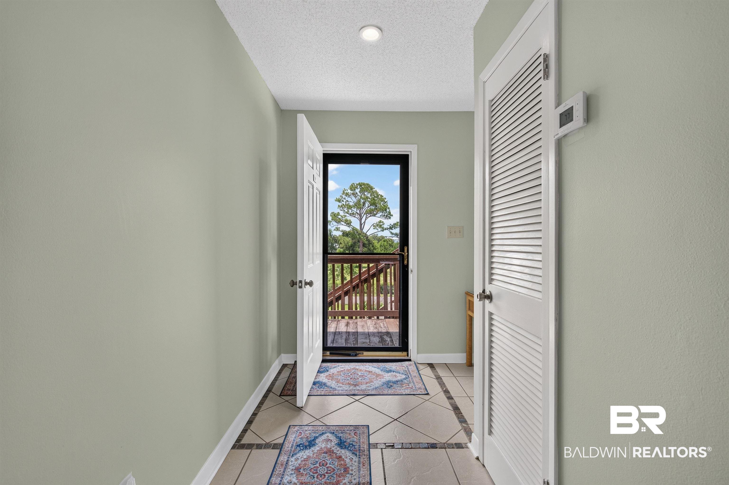 Image 2: Entryway featuring light green wall paint, a white solid panel door, and patterned tile flooring