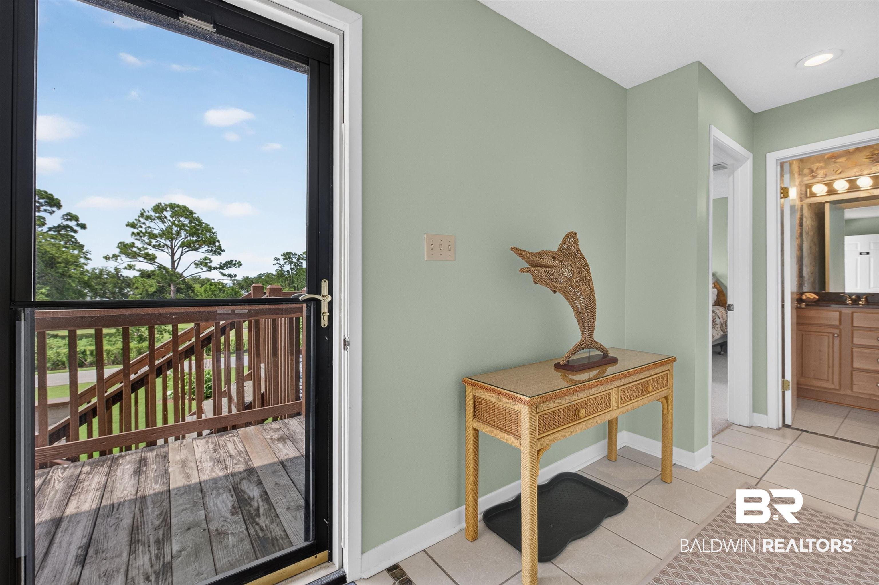 Image 3: Inviting entryway featuring a full-light storm door opening to a wood deck with railings, light green walls, and tile flooring