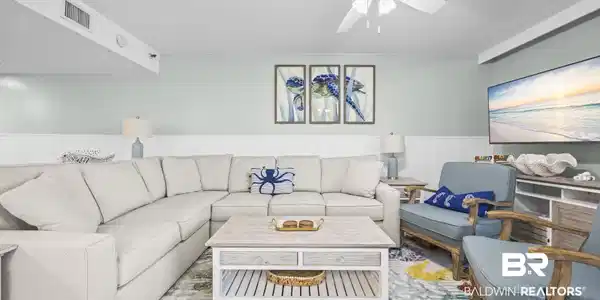 Image 3: Spacious living area featuring a neutral sectional sofa, light wood-finish coffee table, and a ceiling fan