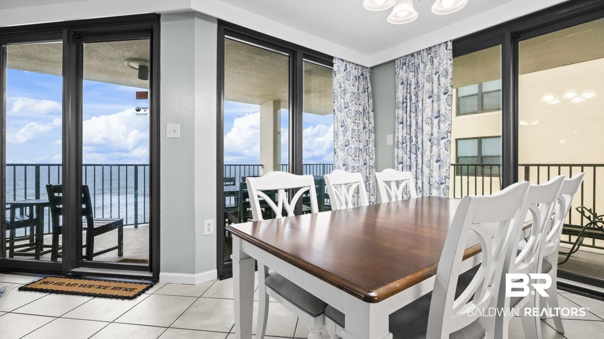 Image 4: Dining area with expansive sliding glass doors opening to outdoor balconies