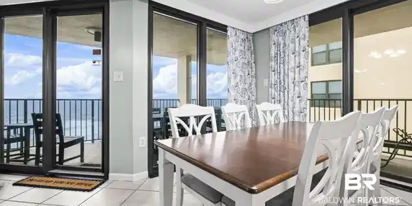Image 4: Dining area with expansive sliding glass doors opening to outdoor balconies