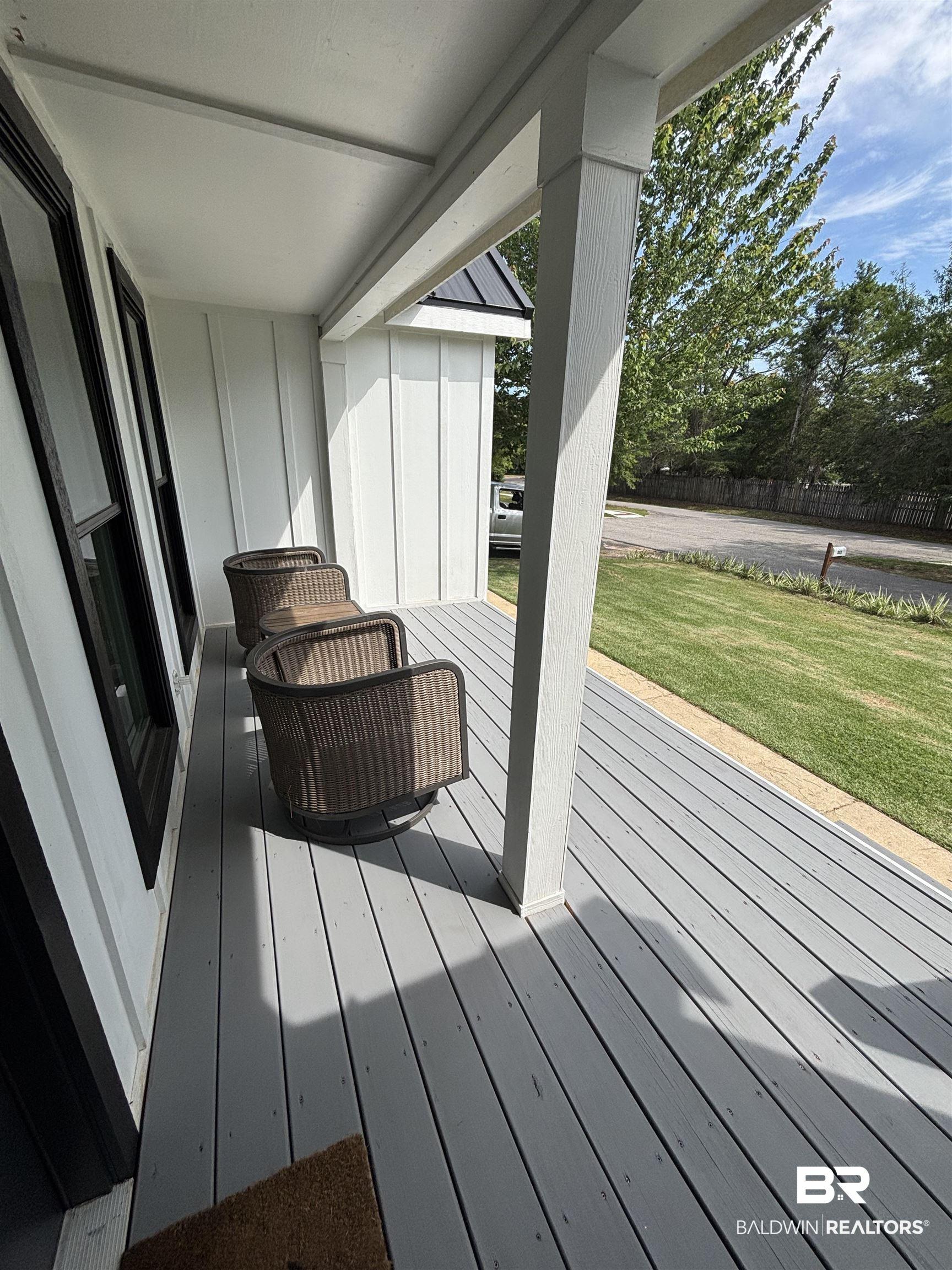 Image 3: Inviting covered porch with gray decking and white board and batten siding
