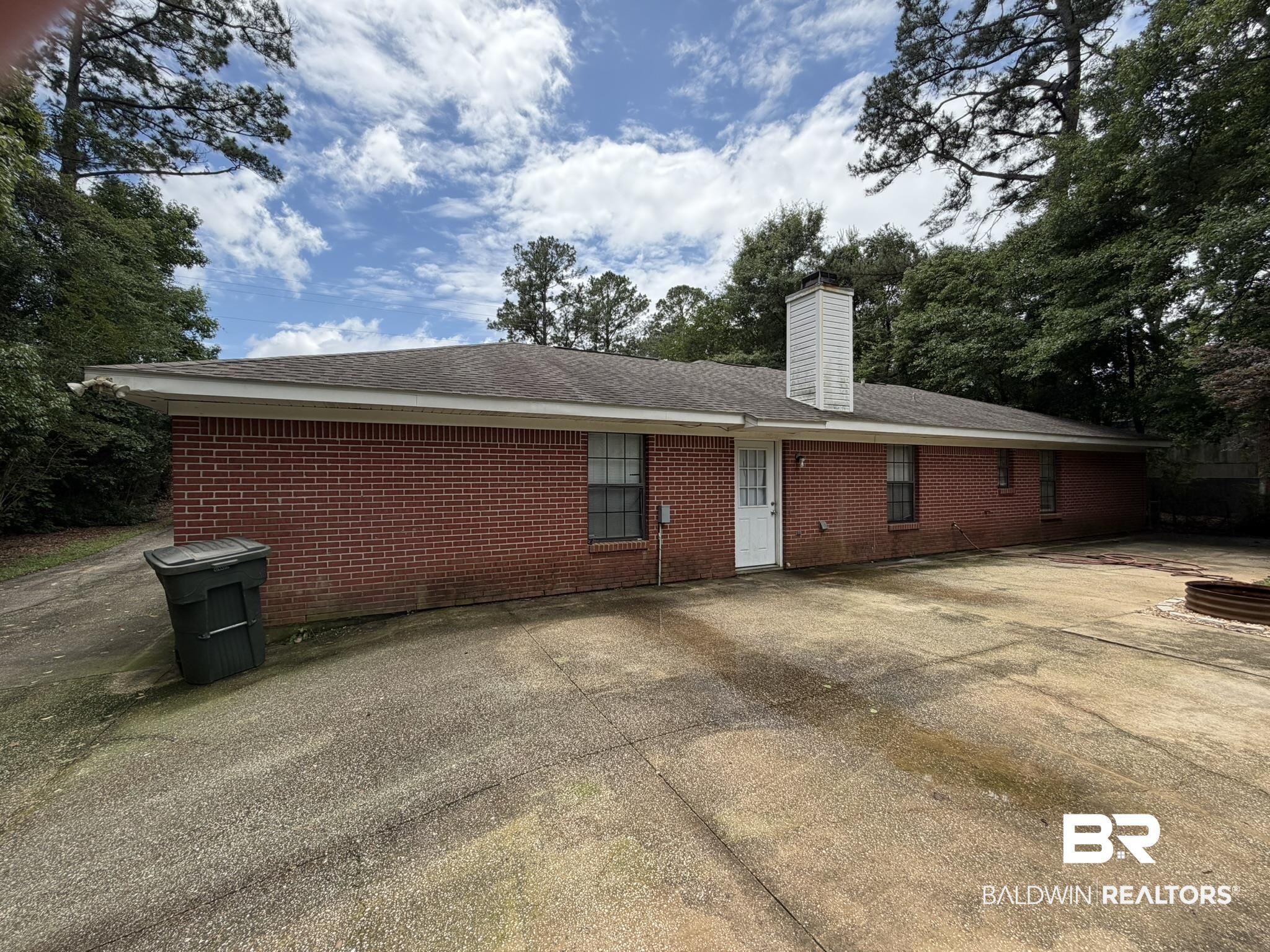 Image 2: Brick exterior featuring multiple windows and a white exterior door