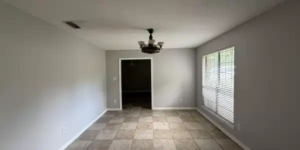 Image 4: Spacious room with large-format tile flooring, neutral wall paint, and a multi-light ceiling fixture