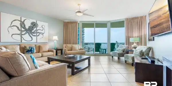 Image 2: Spacious living area featuring neutral-toned tile flooring, light blue wall paint, a ceiling fan with integrated lighting, and expansive glass sliding doors opening to an outdoor area