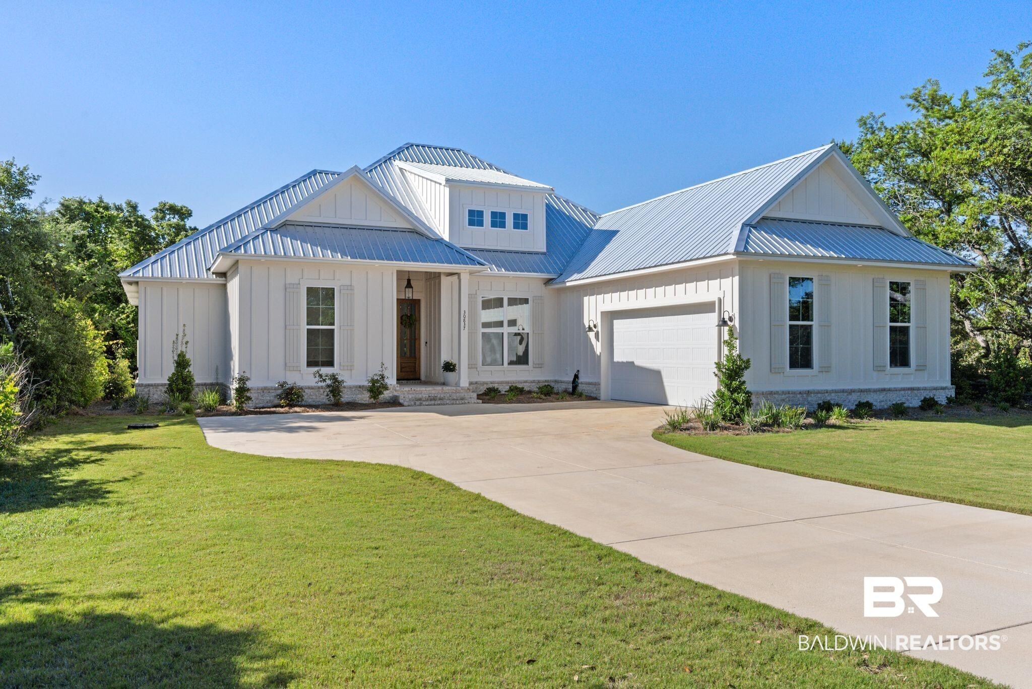 Image 3: Modern farmhouse exterior featuring white vertical board-and-batten siding, a light gray metal roof, and a two-car garage