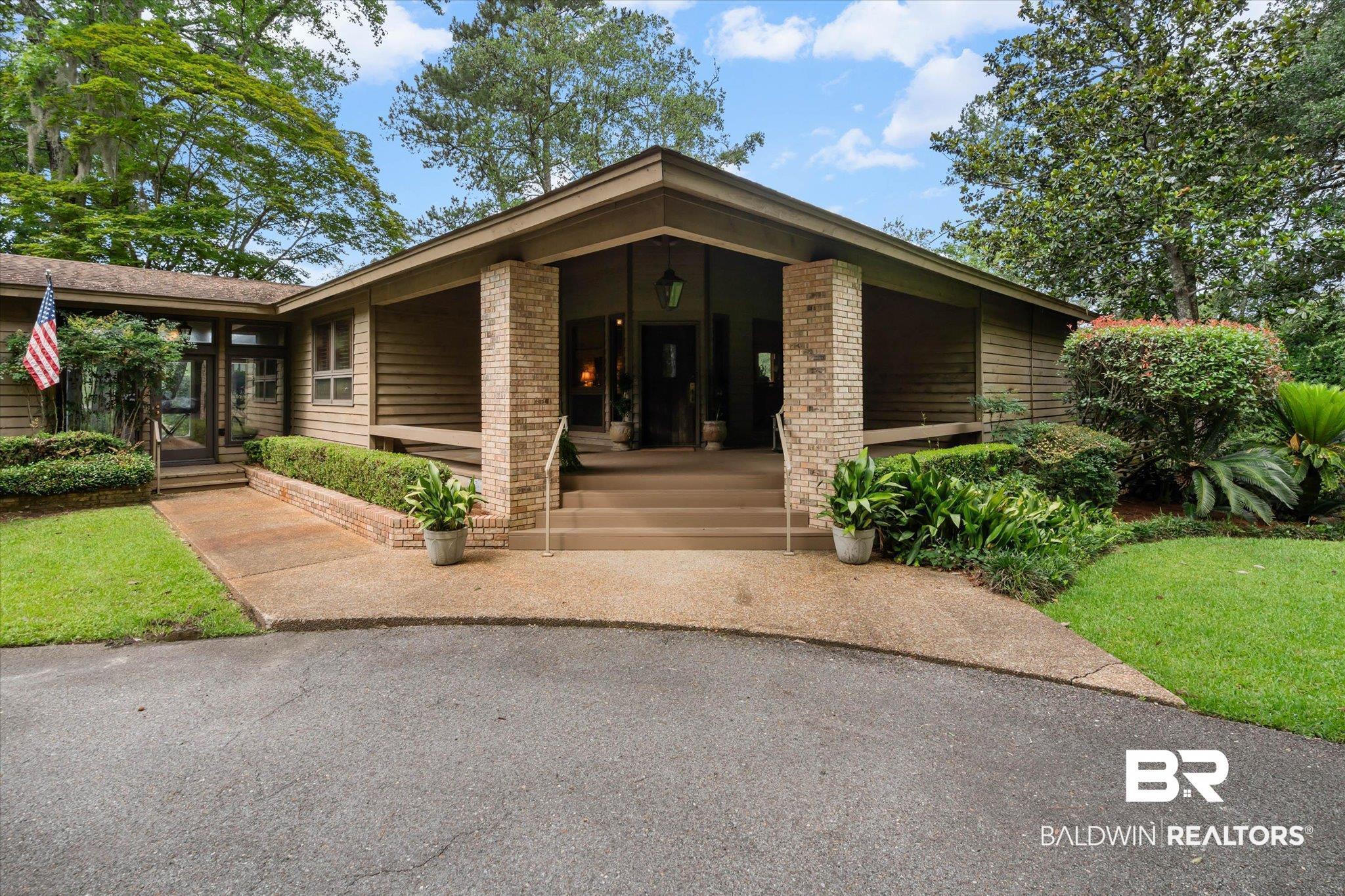 Image 2: Exterior featuring a recessed entry, brick columns, and horizontal wood siding