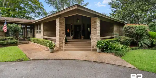 Image 2: Exterior featuring a recessed entry, brick columns, and horizontal wood siding