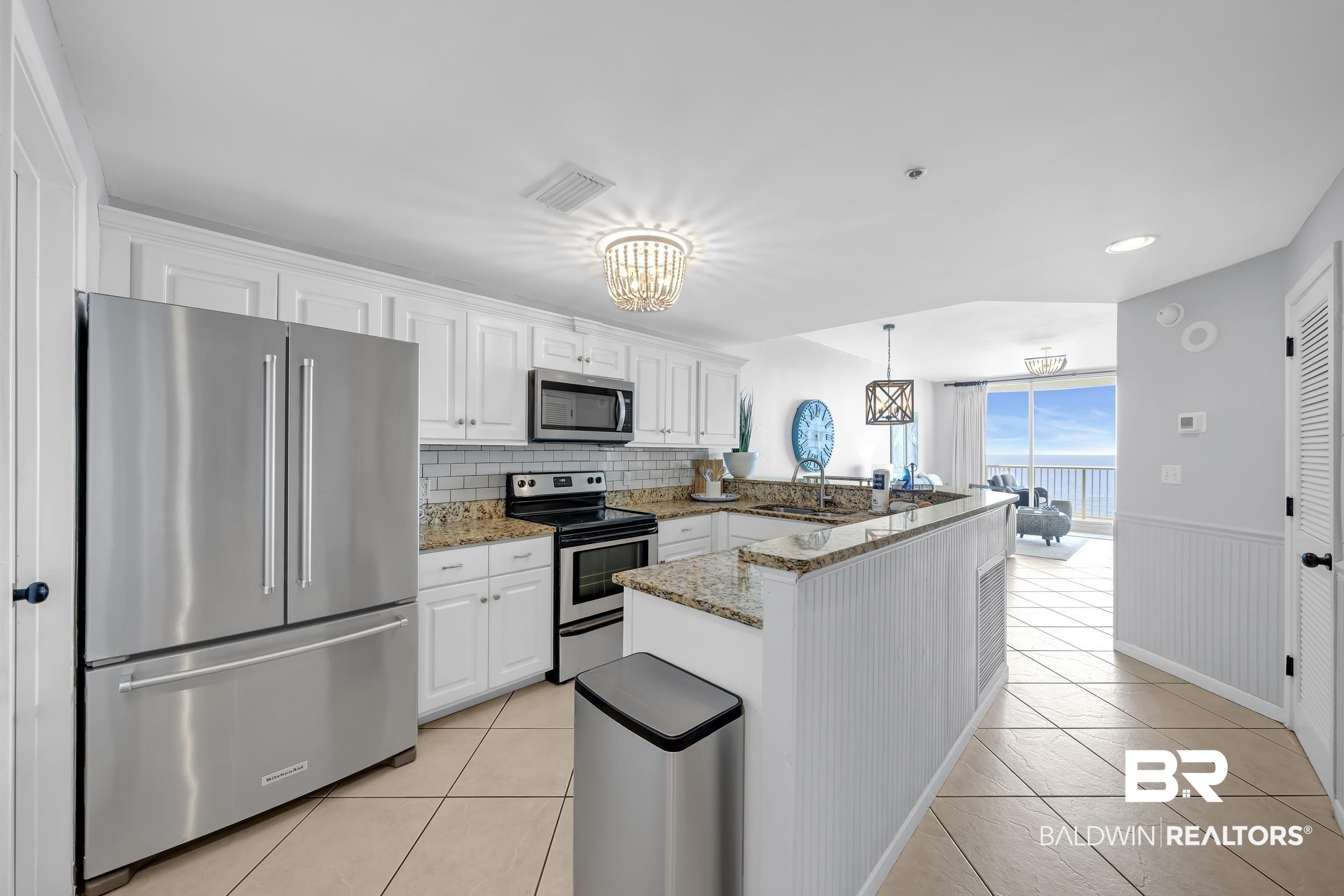 Image 2: Kitchen featuring white cabinetry, granite countertops, subway tile backsplash, and stainless steel appliances