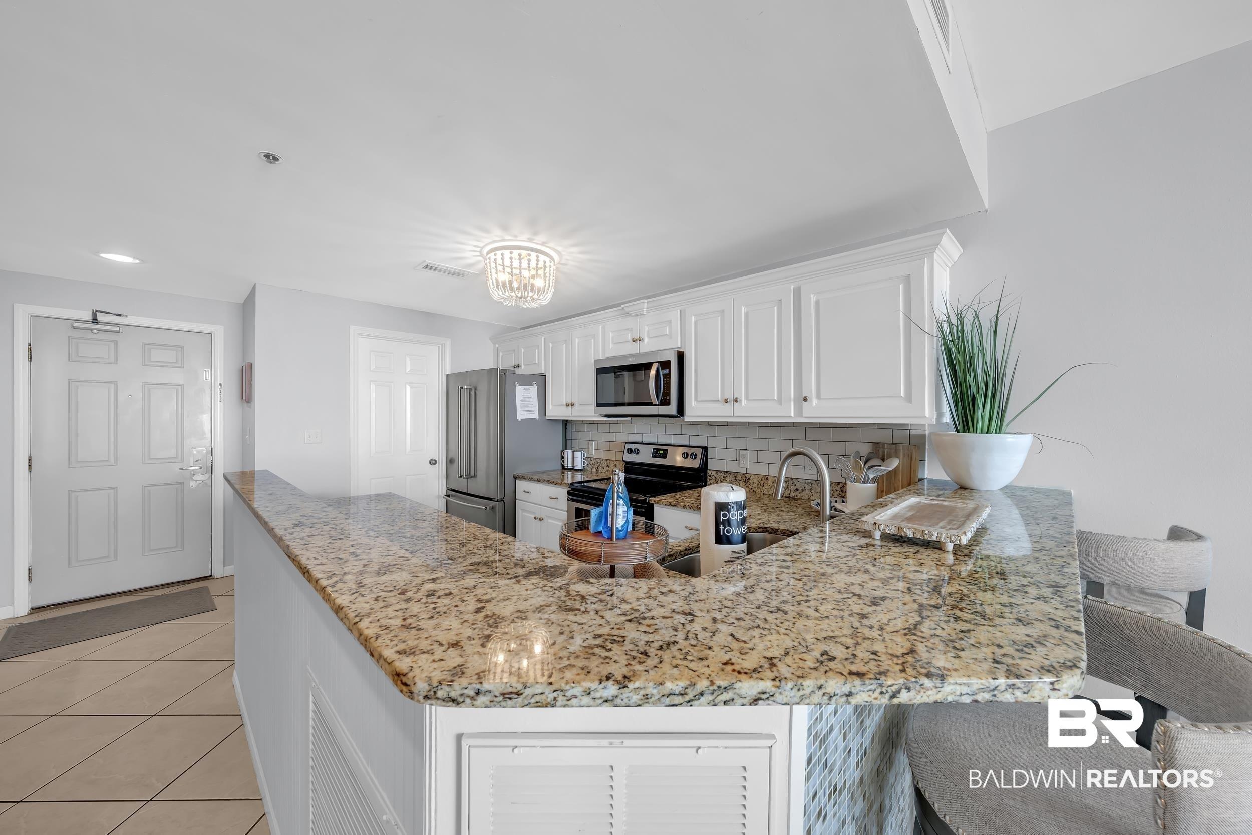 Image 4: Kitchen featuring granite countertops, white cabinetry, a subway tile backsplash, and stainless steel appliances