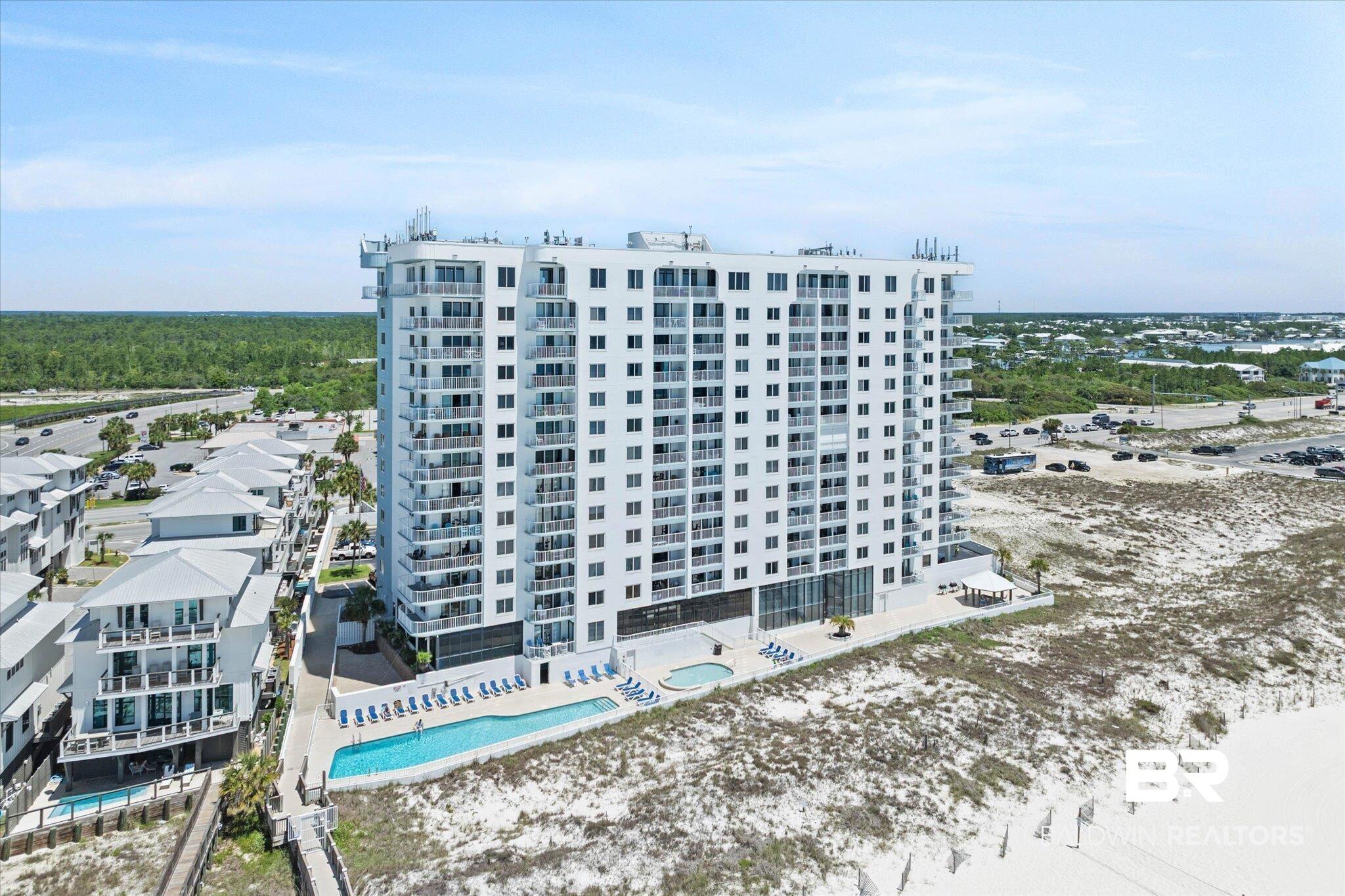 Image 2: Modern multi-story building featuring multiple balconies, ground-level swimming pool, and direct beach access