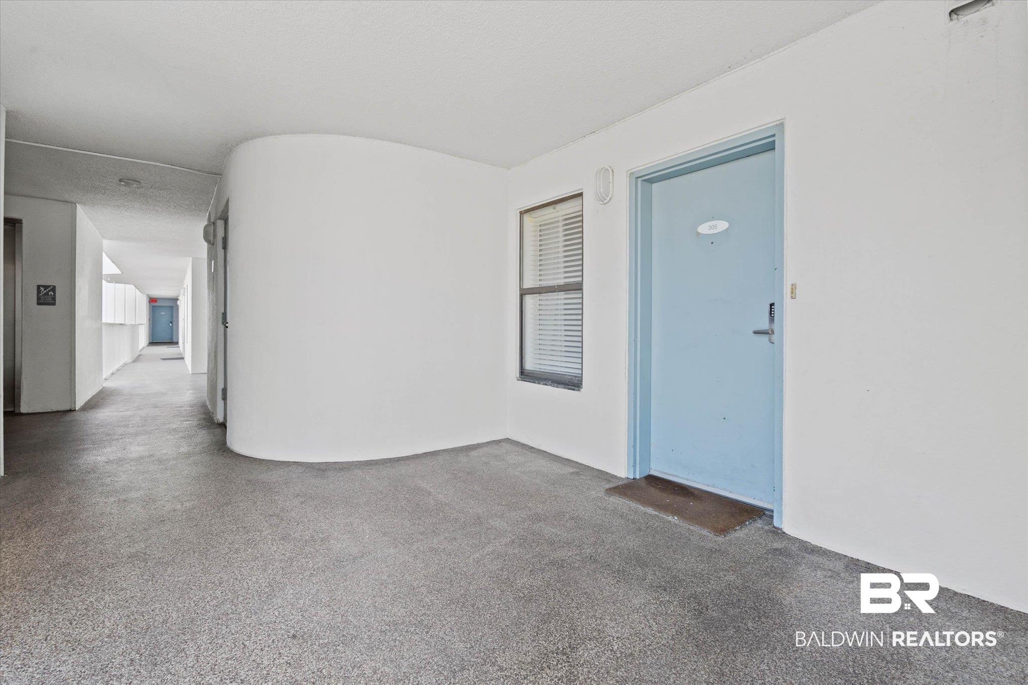 Image 4: Entryway with a light blue door, an exterior wall sconce, and a window featuring horizontal blinds