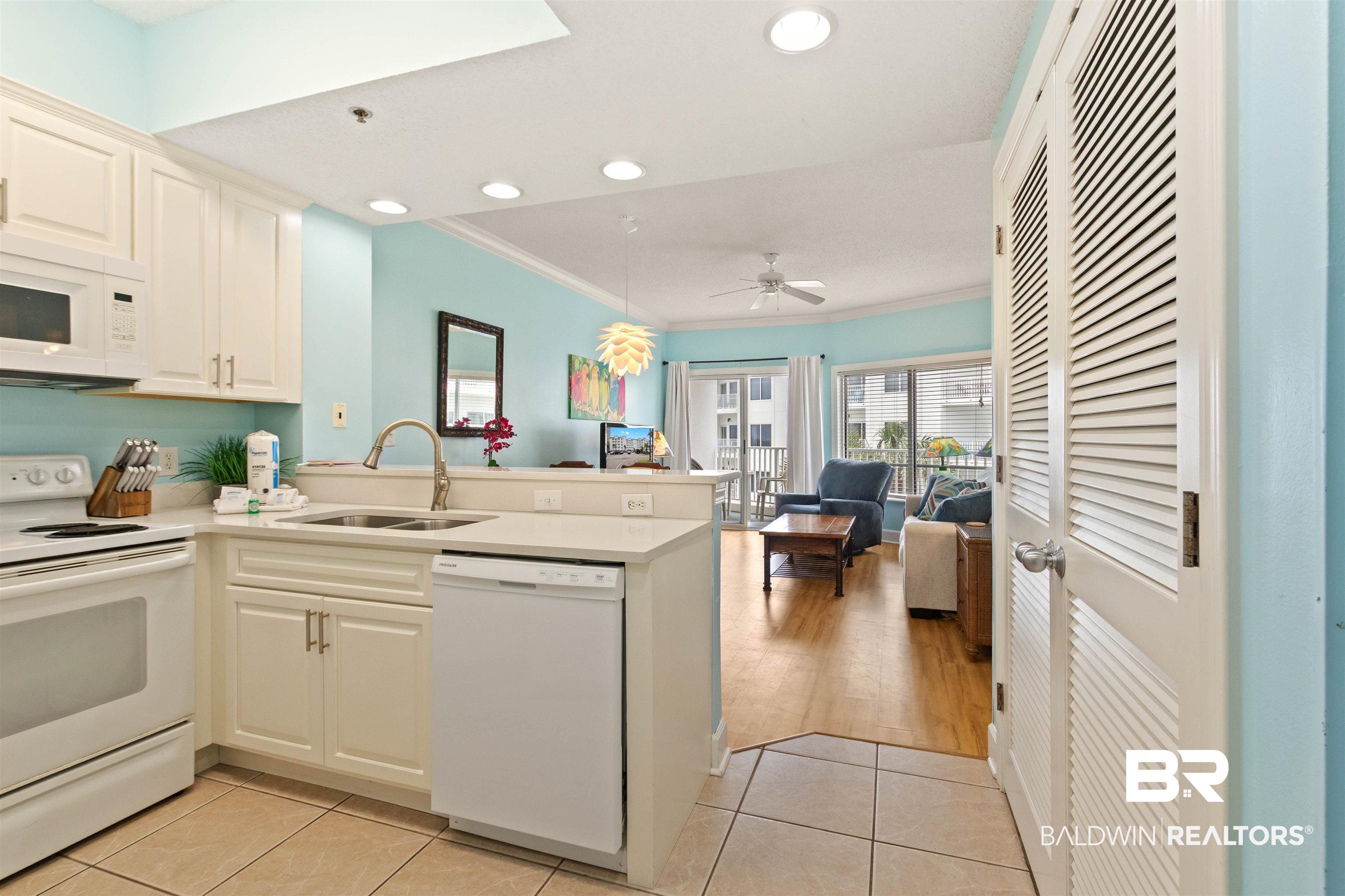 Image 2: Kitchen featuring white cabinetry, solid surface countertops, and white appliances