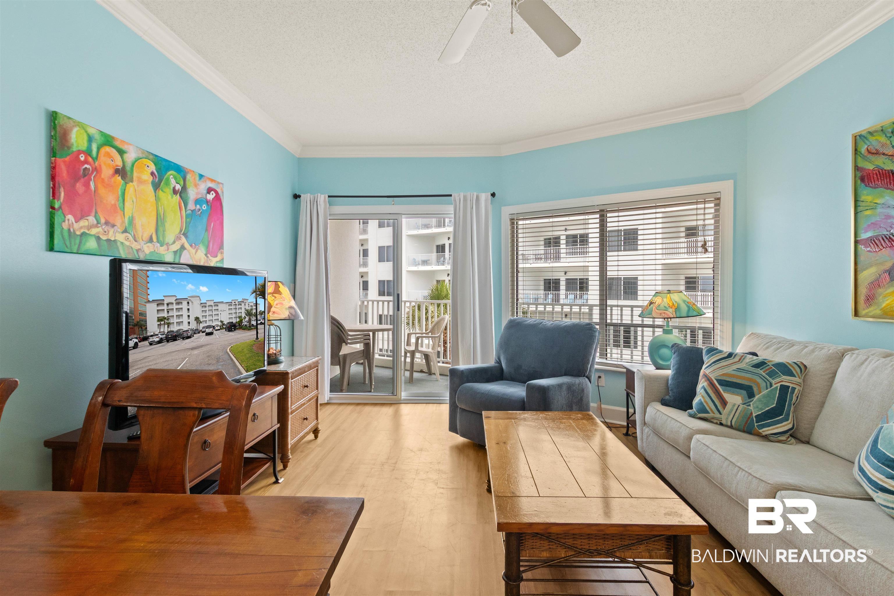 Image 4: Bright living area featuring wood-finish flooring, crown molding, and a ceiling fan