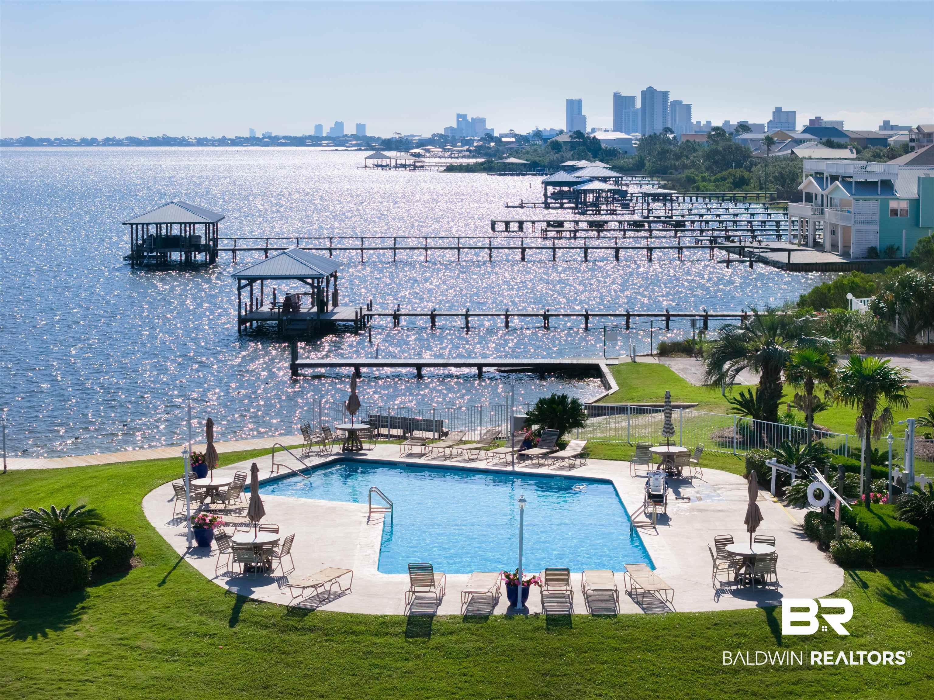 Image 2: Expansive waterfront property featuring a rectangular swimming pool, concrete pool deck, and surrounding manicured lawn