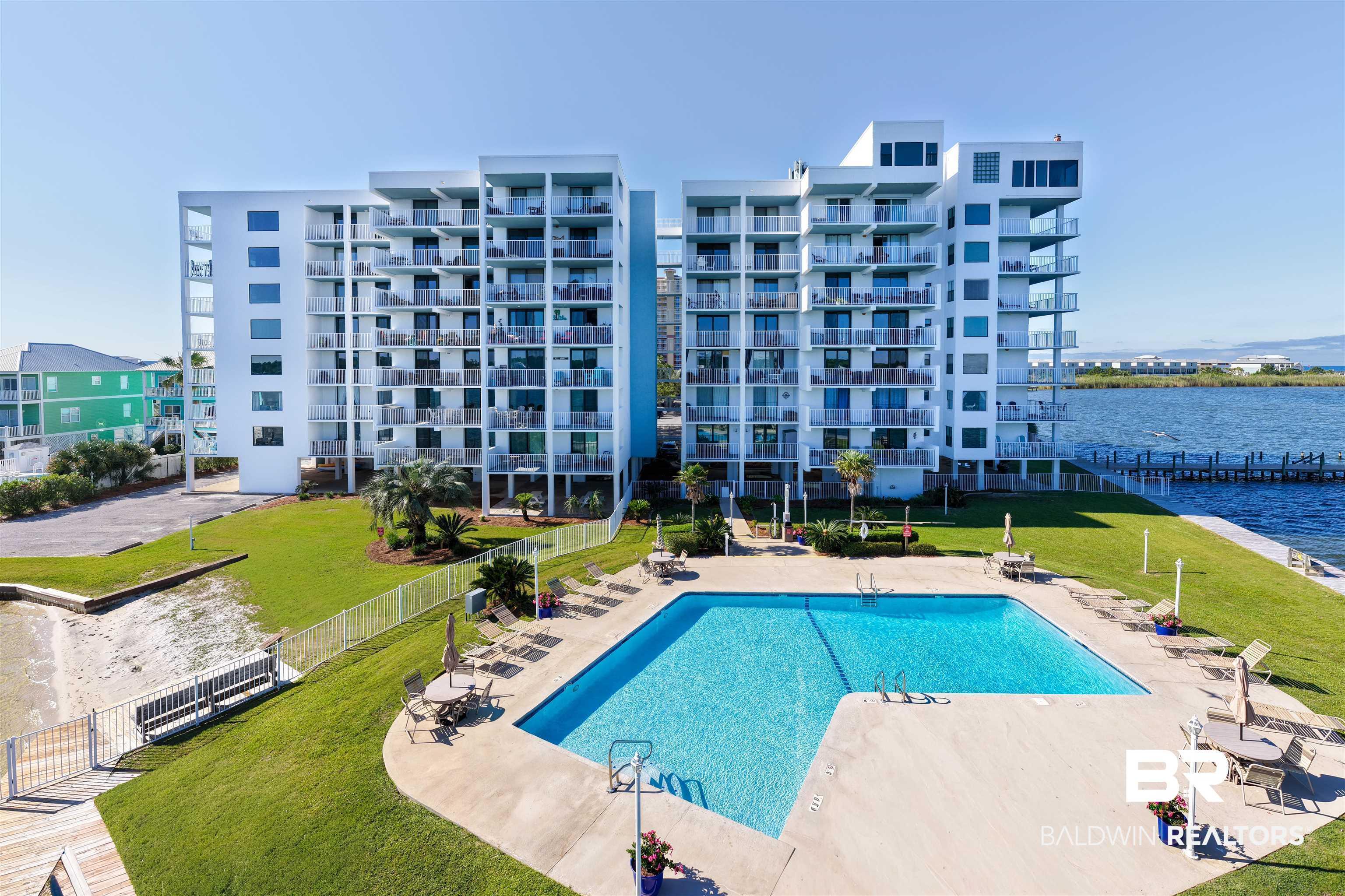 Image 4: Modern multi-story building featuring multiple private balconies overlooking a rectangular swimming pool with surrounding concrete decking