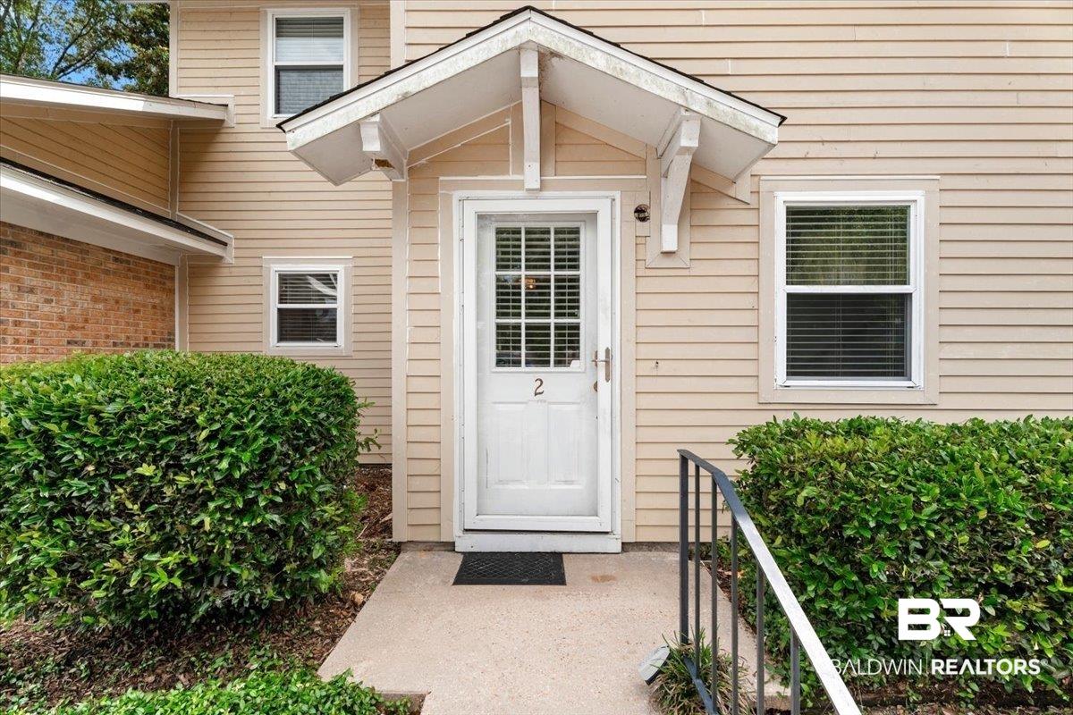 Image 4: Entryway featuring a white paneled door with glass inserts, a protective overhang, and a concrete path